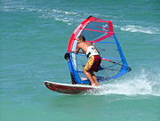 A windsurfer tilts his rig and carves his sailboard to perform a planing laydown jibe or gybe (downwind turn). See sailboarding terms and nomenclature below.